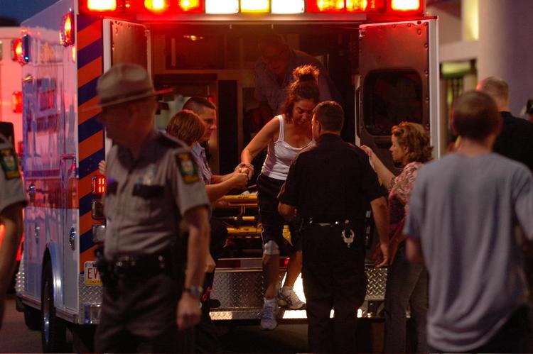 En kvinde hjælpes ud af en ambulance, efter at hun er blevet behandlet uden for fitnesscenteret. 