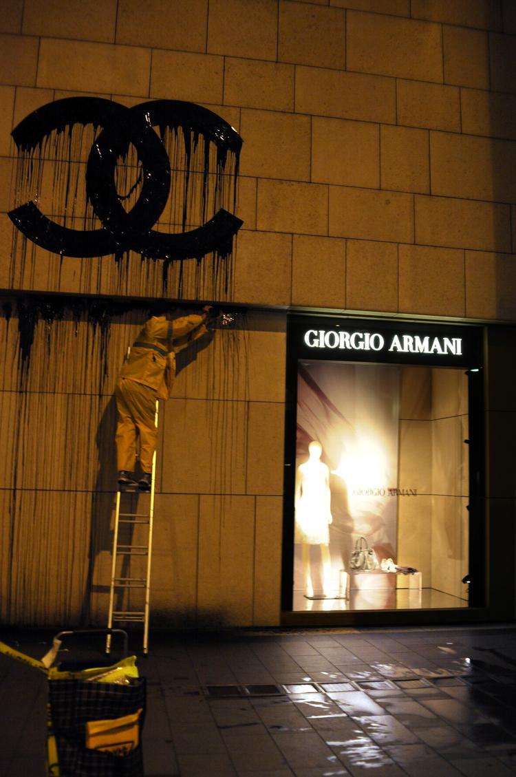 Her maler Zevs Chanel-logoet på Armani-butikkens mur. En rengøringsmand, der blev hyret af butikken i Hongkong, kunne ikke få Zevs' ulovlige Chanel-logo væk.  Et særligt kemisk middel fra Danmark måtte sendes af sted. Nu er logoet væk. Foto: Edwin Lee 