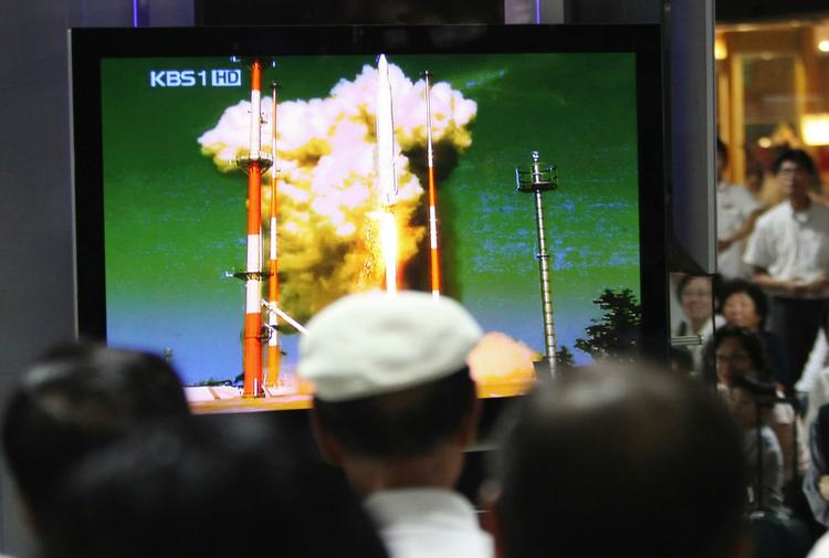 Opsendingen af Sydkoreas førstee rumraket blev sendt på tv og fulgt over hele landet - her har togrejsende samlet sig foran et tv på en banegård i Seoul. 