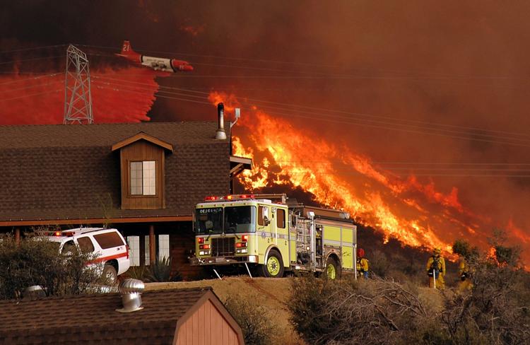 Brandfolk på jorden og i luften kæmper for at redde et hus i Acton i Californien. 