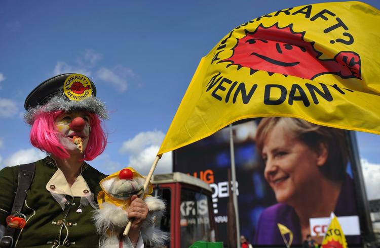 En demonstrant vifter med sit flag med teksten 'Atomkraft - nej tak' foran en valgplakat med  Angela Merkels portræt. 