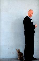 Som en Thomas Blachman står Henrik Jensen på sin bogs forside i jakkesæt og skaldepande. Men nu med kat. Udsnit af omslag: Imperiet med foto af Mette Frandsen 