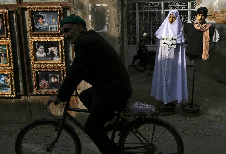 En mand cykler forbi en mannequin, som overholder myndighedernes regler for udstillingsdukker i byen Mashhad i Iran. 