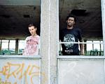 Selv om Daddy G og 3D, der i dag udgør Massive Attack ligner sig selv nogenlunde fra gruppens tidlige plakater og stadig bor i Bristol, hvor alt startede, er der sket store forandringer, mener de to i vinduet til deres studie. »Hele verden er blevet protektionistisk, og alt handler om penge. Det har ødelagt meget her«, mener de to. PR-foto: Hamish Brown 