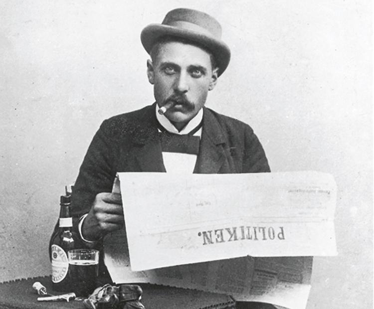 Henrik Cavling fotograferet i 1899 som fyrreårig reporter med cigar, skindhandsker og en øl på cafebordet. 