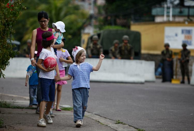 En familie går forbi den brasilianske ambassade i Tegucigalpa, hvor landets tidligere præsident har søgt tilflugt. Ambassaden er bevogtet af honduranske soldater. 