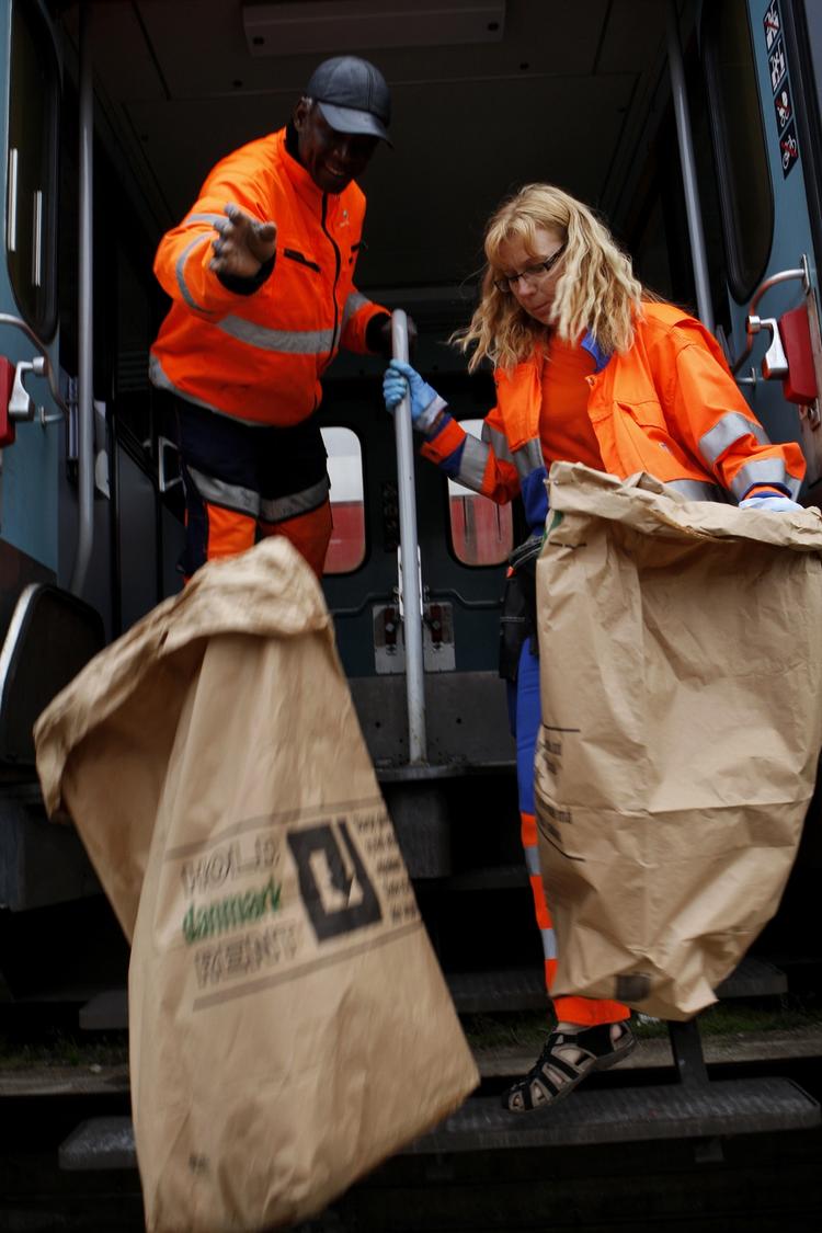 Eddy Sanyang og Anita Olander skal have tunge affaldssække en meter ned fra togene. 
