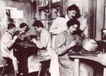 Georg Jensens smedje i starten af 1900 tallet, hvor Georg Jensen er ved at instruere en ny medarbejder. 