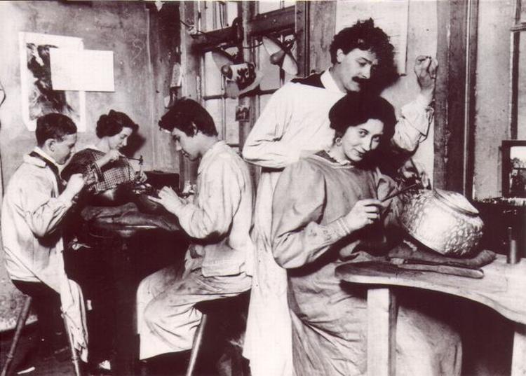 Georg Jensens smedje i starten af 1900 tallet, hvor Georg Jensen er ved at instruere en ny medarbejder. 