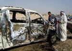 Folk ved en ødelagt bil efter bombeangreb i Ramadi, der ligger 115 kilometer vest for hovedstaden Bagdad. 