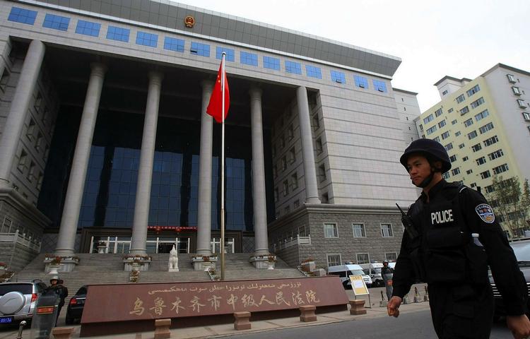 En kinesisk politibetjente på patrulje foran den domstol i Urumqi, hvor  seks mænd i dag fik dødsstraf efter den etniske uro tidligere på året. 