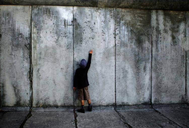En knægt rører ved betonplader fra Berlinmuren ved mindesmærket på Bernauer Strasse. Der findes over 1.000 små rester af Berlinmuren, og de er nu alle lagt ud på et interaktivt online-kort. Arkivfoto fra august i år. 