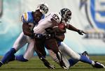 Denver Broncos Knowshon Moreno trækkes ned af to San Diego Chargers-folk. Tacklingen er så hård, at hjelmen flyver af Kevin Burnett. 