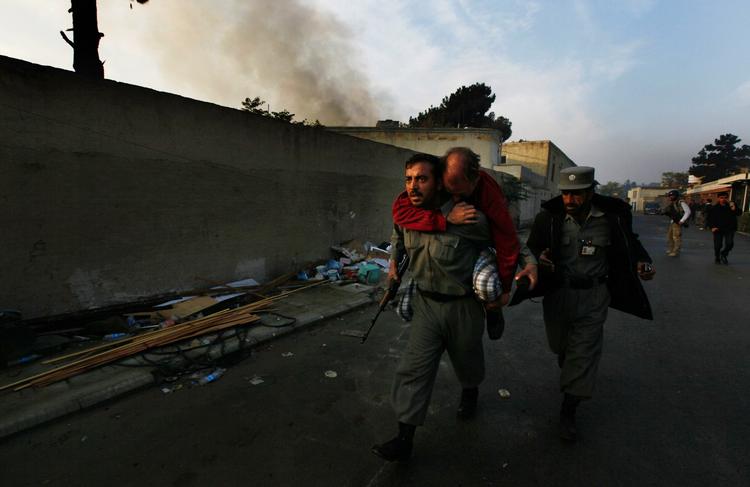 Terroroffer: Tysker bæres væk fra angrebet i Kabul af afghansk politibetjent. 