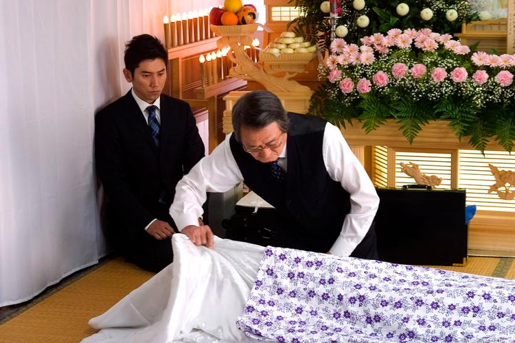 De japanske klædedragter skal lægges i de rette folder, når den døde skal sendes af sted på sin sidste rejse. Daigo (tv.) spilles af Masahiro Motoki. Foto: Miracle Film 