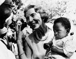 fingersprog. Dronning Ingrid med baby på armen i Tanzania. »Jeg har selv tre«, viser hun med fingrene til barnets mor. Foto: Allan Moe 
