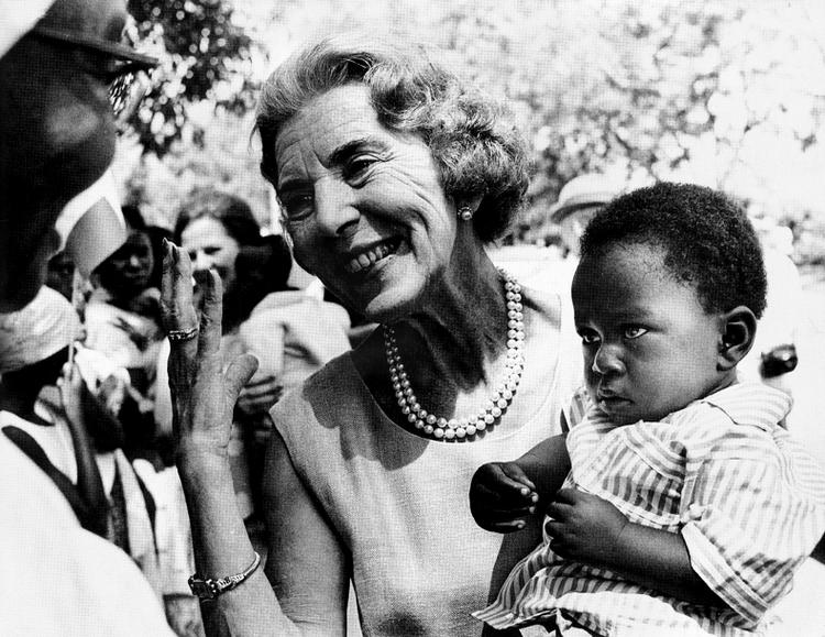 fingersprog. Dronning Ingrid med baby på armen i Tanzania. »Jeg har selv tre«, viser hun med fingrene til barnets mor. Foto: Allan Moe 