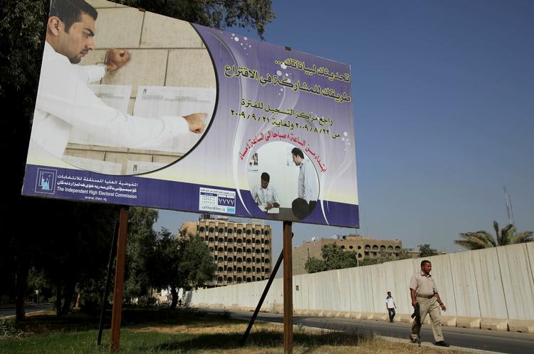 Valgkamp. En sikkerhedsvagt går forbi en valgplakat  i det centrale Bagdad. Irak skal efter planen til valg i januar. 