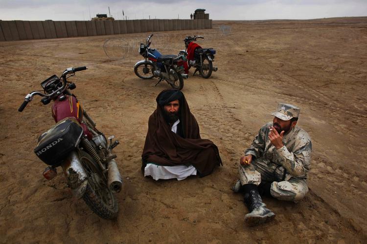 Vagt. En afghansk grænsepolitibetjent på arbejde i weekenden snakker med lokal mand i Afghanistans Helmand-provins. I dag mistede mange af hans kolleger livet. 