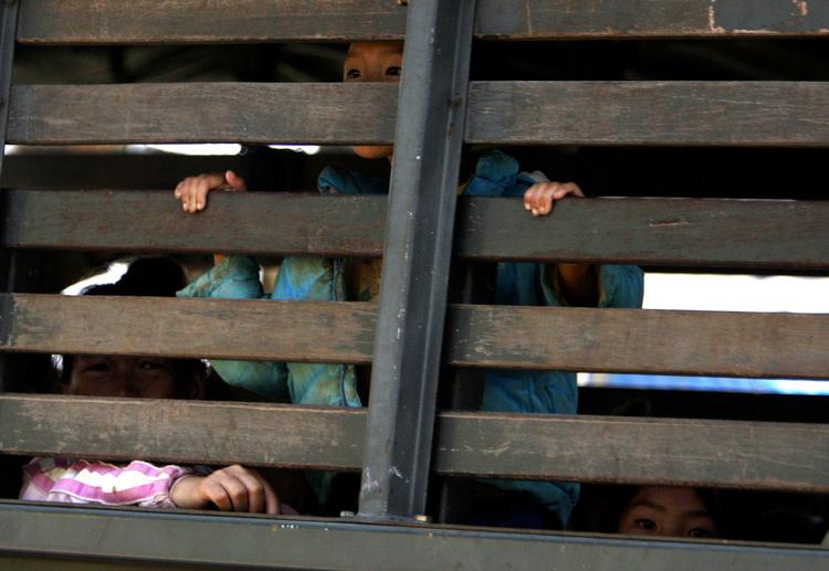 udvist. Hmong-flygtninge kigger ud fra den lastbil, der skal fragte dem fra flygtningelejren i Thailand til Laos. 