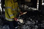 Brandskade. En brandmand gennemsøger ødelagt bohave i et af de huse, der er blevet raseret af ilden. 