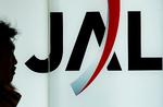 fyringsrunde. En passager går forbi et logo for japan Airlines i Haneda lufthavnen i Tokyo. Selskabet lægger op til at fyre over 15.000 for at sikre en eksistens. 