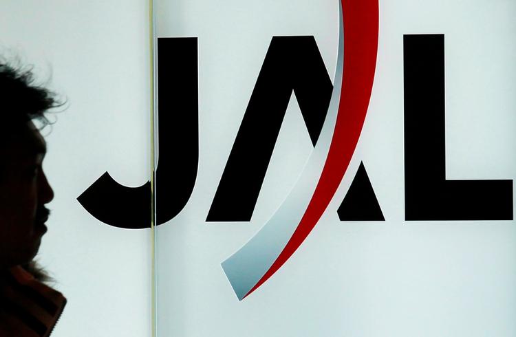 fyringsrunde. En passager går forbi et logo for japan Airlines i Haneda lufthavnen i Tokyo. Selskabet lægger op til at fyre over 15.000 for at sikre en eksistens. 