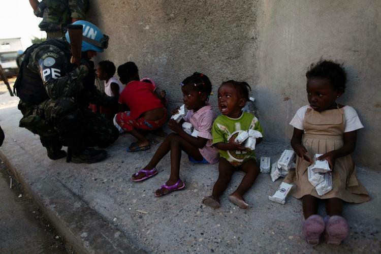 Venlighed. En brasiliansk FN-soldat forsøger at trøste en lille pige ved et improviseret center, der fordeler nødhjælp i Cite Solei-området i Port-au-Prince. 