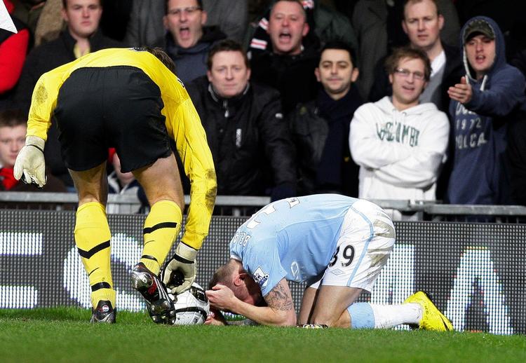 assistance. Manchester Uniteds målmand Edwin Van Der Sar hjælper den liggende Manchester City-spiller Craig Bellamy, efter han er blevet ramt af en mønt. Et par flasker blev også kastet efter waliseren. 