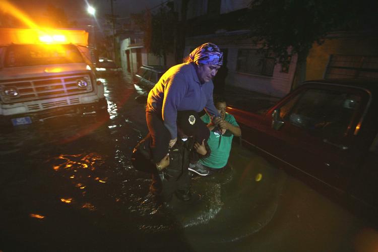 Evakuering. Redningsarbejdere evakuerer kvinde fra vandmasserne i oversvømmet kvarter i Mexico City. Regnskyl har kostet 44 mexicanere livet. 