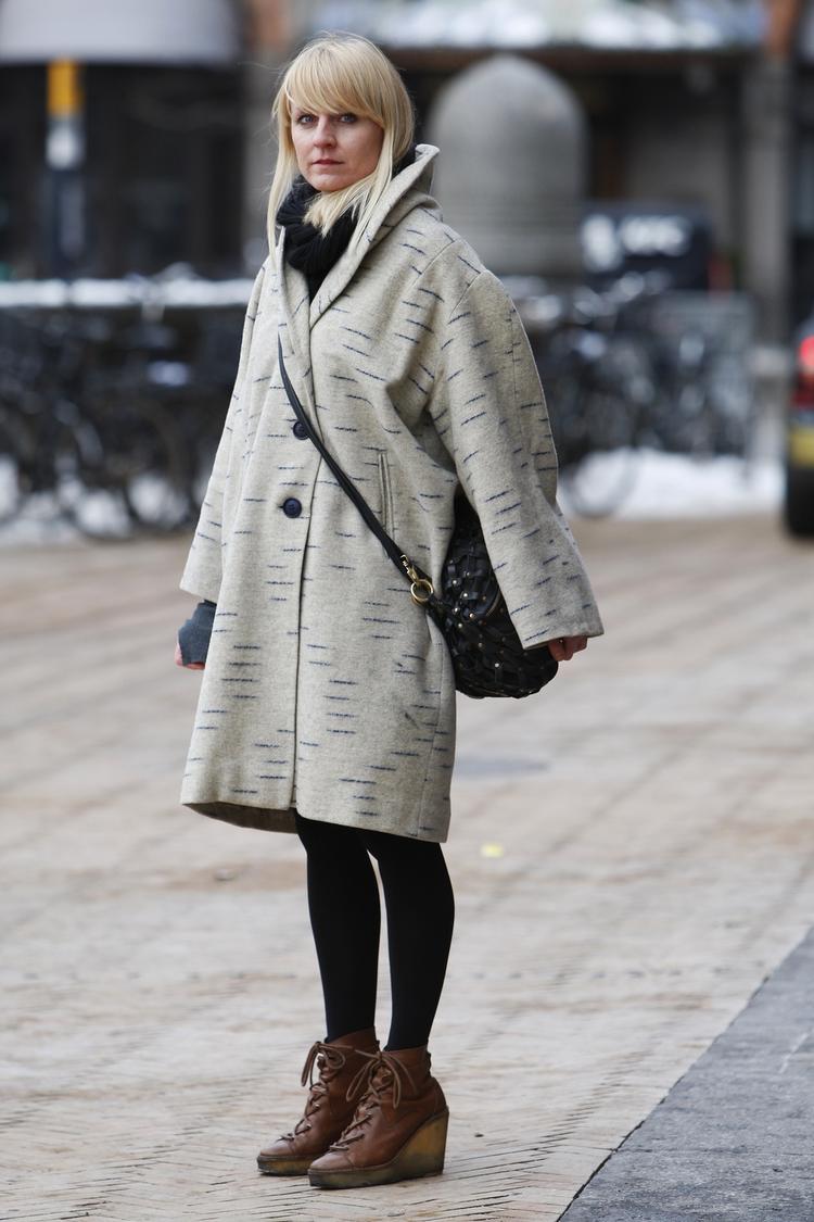 Rikke Kjær (33 år). Modeeksperten siger: »Flot frakke i et oversize-look. Snørestøvlerne med plateau ser man mange af denne vinter. Det er ret fint, at de er i brunt læder. Det bryder det grå/ sorte look og skaber kontrast«. 