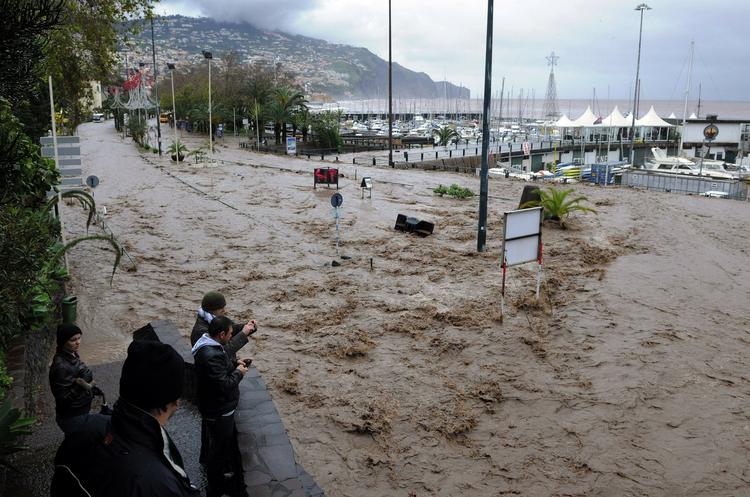 Oversvømmelse. Mudret vand strømmer ned mod havnen i Madeiras største by Funchal. Vandmasserne har kostet adskillige livet. 