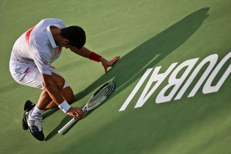 udmattet. En glad Novzak Djokovic synker sammen efter at have vundet den regnvejrsafbrudte finale i Dubai. 