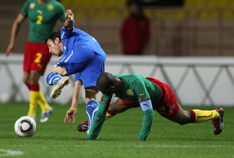 Nedtur. Samuel Eto'o i nærkamp med Italiens debutant Andrea Cossu. 
