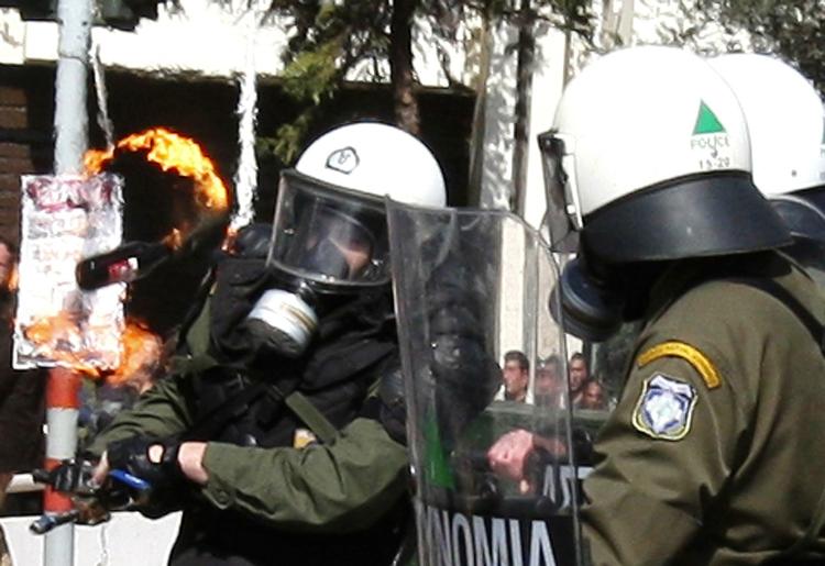 Gadekampe. En betjent undviger en benzinbombe under demonstrationerne i Athen i dag. 