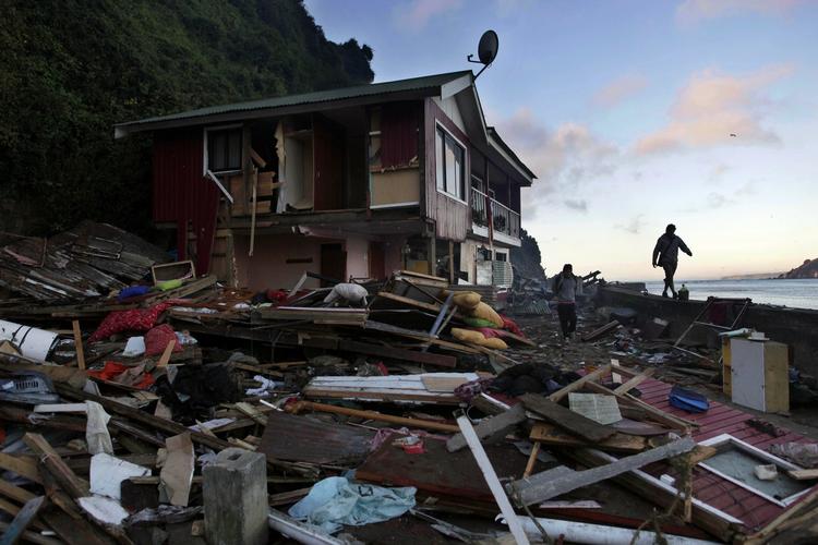 ØDELÆGGELSER. Flere personer går forbi en beskadiget hus i Chile. 