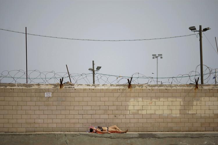 En israelsk kvinde tager solbad ved Israels barriere indtil den besatte Vestbred. Nordiske virksomheder kvitter nu investeringer i et af de teknologiselskaber, der har leveret overvågningsudstyr til muren. 