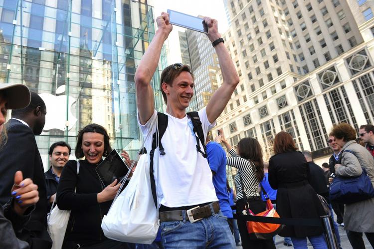 Udlændinge fra hele verden er rejst til New York i USA for at få fingre i den nye iPad fra Apple. Her ses Mike Heinsius fra Holland, der hæver sin nye iPad højt i vejret. 