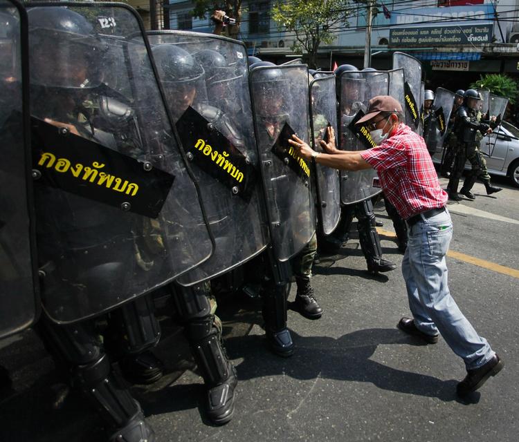 Demonstrant forsøger at tilbageholde thailandske soldater. 