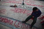 VENTETID. Thaier tager et hvil nær demokratimonumentet i Bangkok, hvor vejbelægningen er fyldt med anti-regerings-grafitti. 