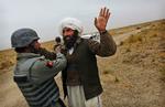 Tjek. En afghansk politirekrut undersøger en landsmand ved en kontrolpost nær Gereshk By. Nogle af hans kolleger har angiveligt været involveret i drab på mindreårig pige. 