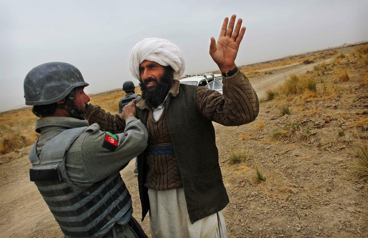 Tjek. En afghansk politirekrut undersøger en landsmand ved en kontrolpost nær Gereshk By. Nogle af hans kolleger har angiveligt været involveret i drab på mindreårig pige. 