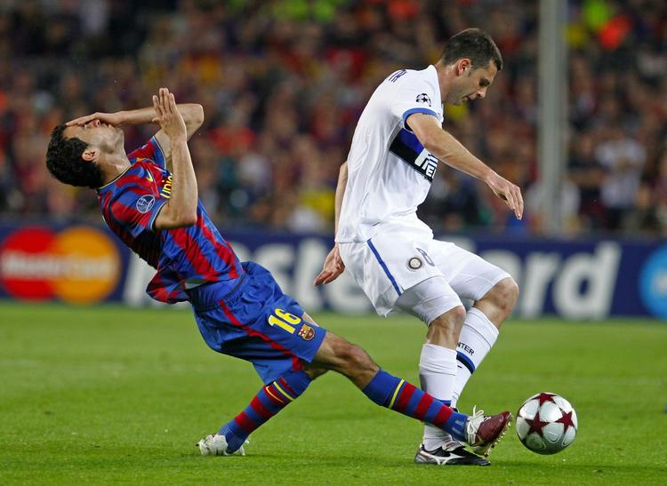Nærkampan. Motta dribler videre, mens Busquets er på vej ned på græsset. 