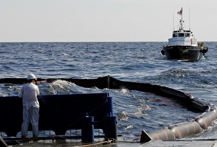 Læk. En arbejder kigger ned på indespærringen af der, hvor et rør lækker omkring 600.000 liter olie om dagen. 
