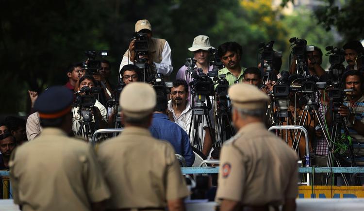 Medieinteresse. Indisk politi holder øje med pressen, der venter i spænding uden for retsbygningen i Mumbai. 
