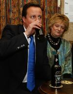 Spænding. David Cameron får lidt at drikke, mens han ser stemmetallene tikke ind. 