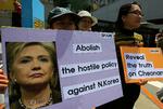 Demonstranter holder billeder af Hillary Clinton i forbindelse med hendes besøg i Seoul i dag. 