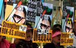 Sydkoreanske demonstranter råber slagord, mens de holder billeder af den nordkoreanske leder Kim Jong II. 