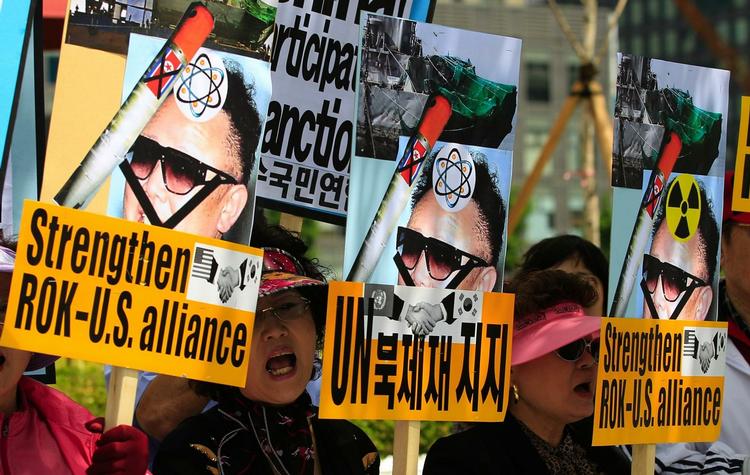 Sydkoreanske demonstranter råber slagord, mens de holder billeder af den nordkoreanske leder Kim Jong II. 