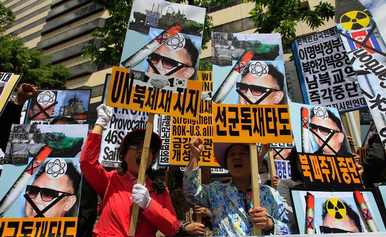 Sydkoreanske demonstranter råber slagord, mens de holder billeder af den nordkoreanske leder Kim Jong II. 
